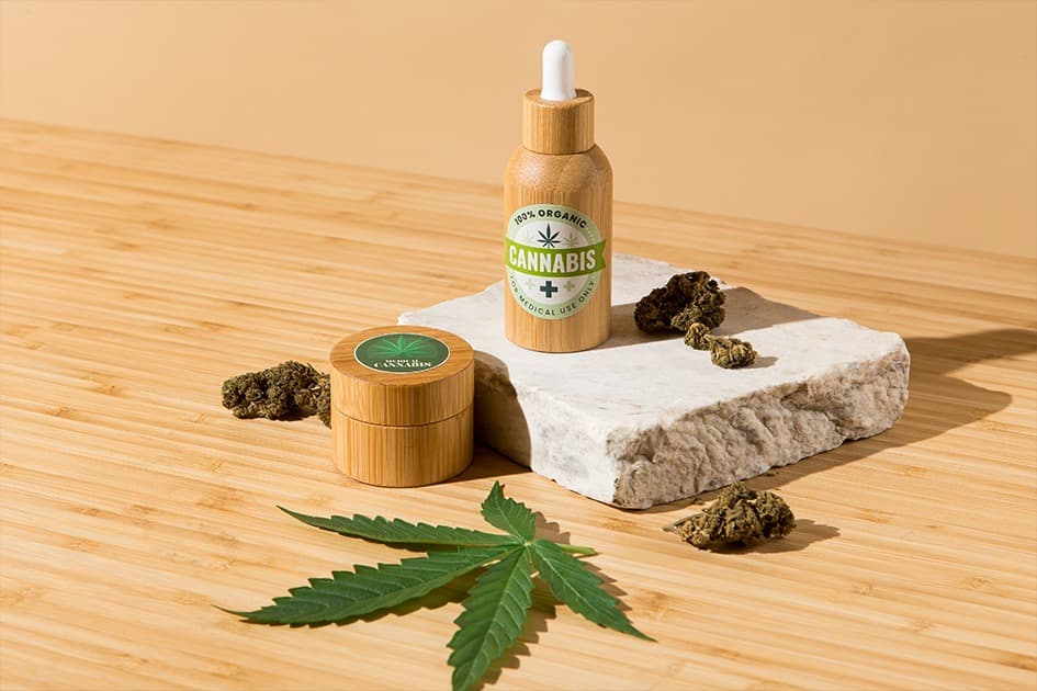 Sustainable bamboo CBD packaging with dropper bottle and jar beside a hemp leaf